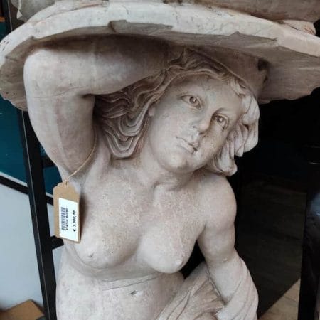 Statua in marmo raffigurante una donna che regge una mensola, scolpita in un unico blocco.