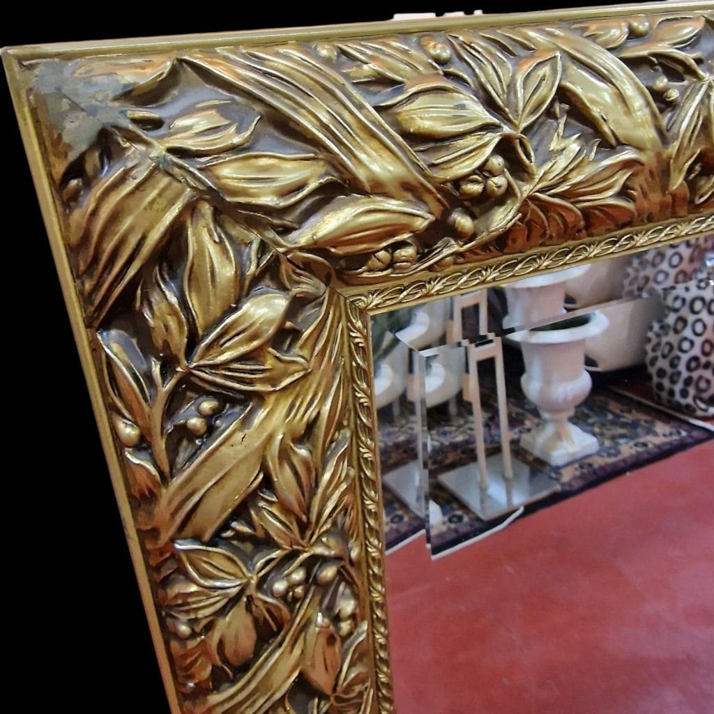 Specchiera lavorata in legno dorato con cornice intagliata e specchio bisellato