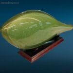 Scultura in vetro di Murano verde con scaglie d'oro raffigurante un elegante pesce su supporto in legno.