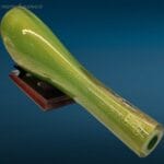 Scultura in vetro di Murano verde con scaglie d'oro raffigurante un elegante pesce su supporto in legno.